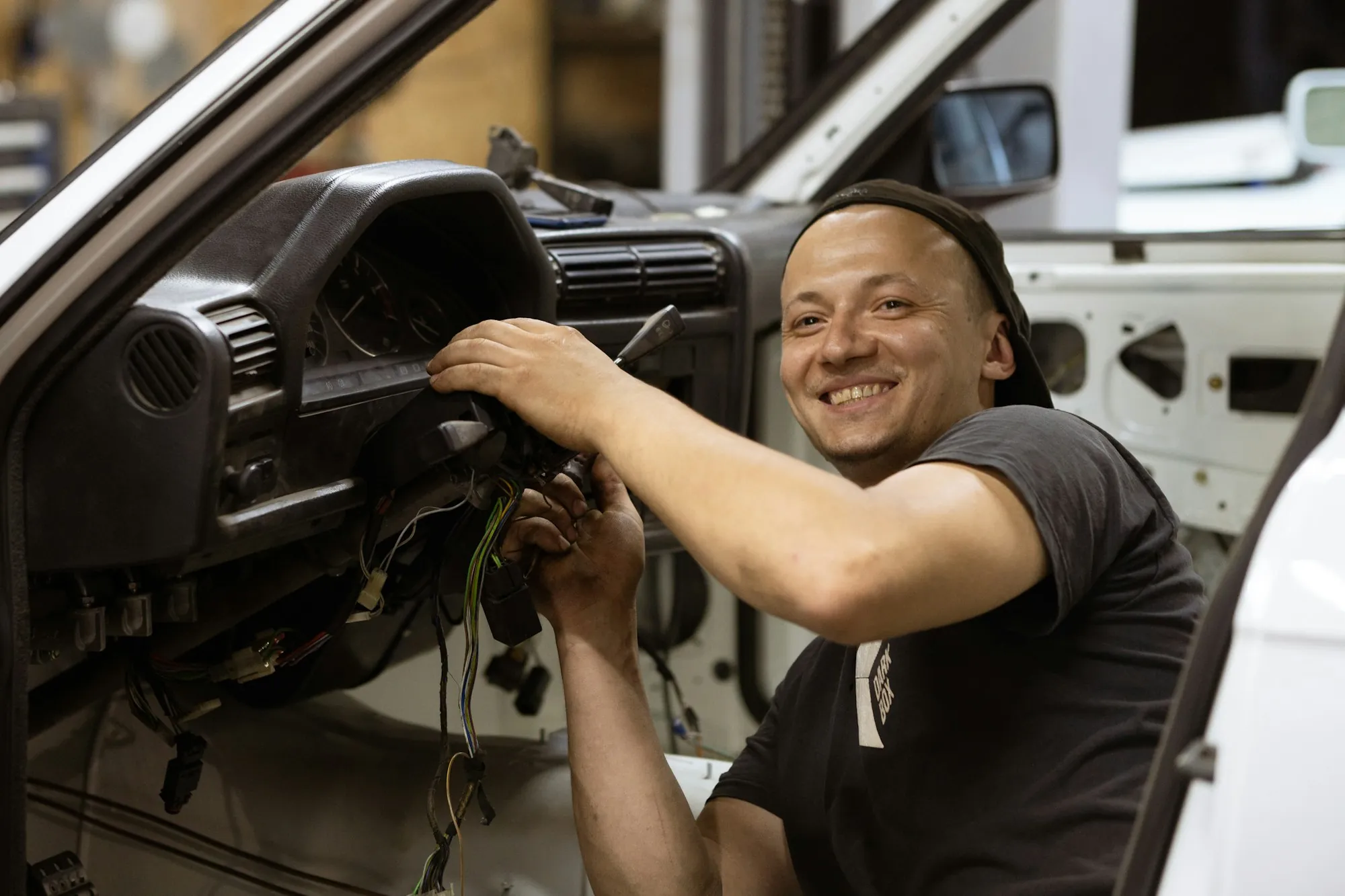 Smiling technician working under the dashboard of a vehicle