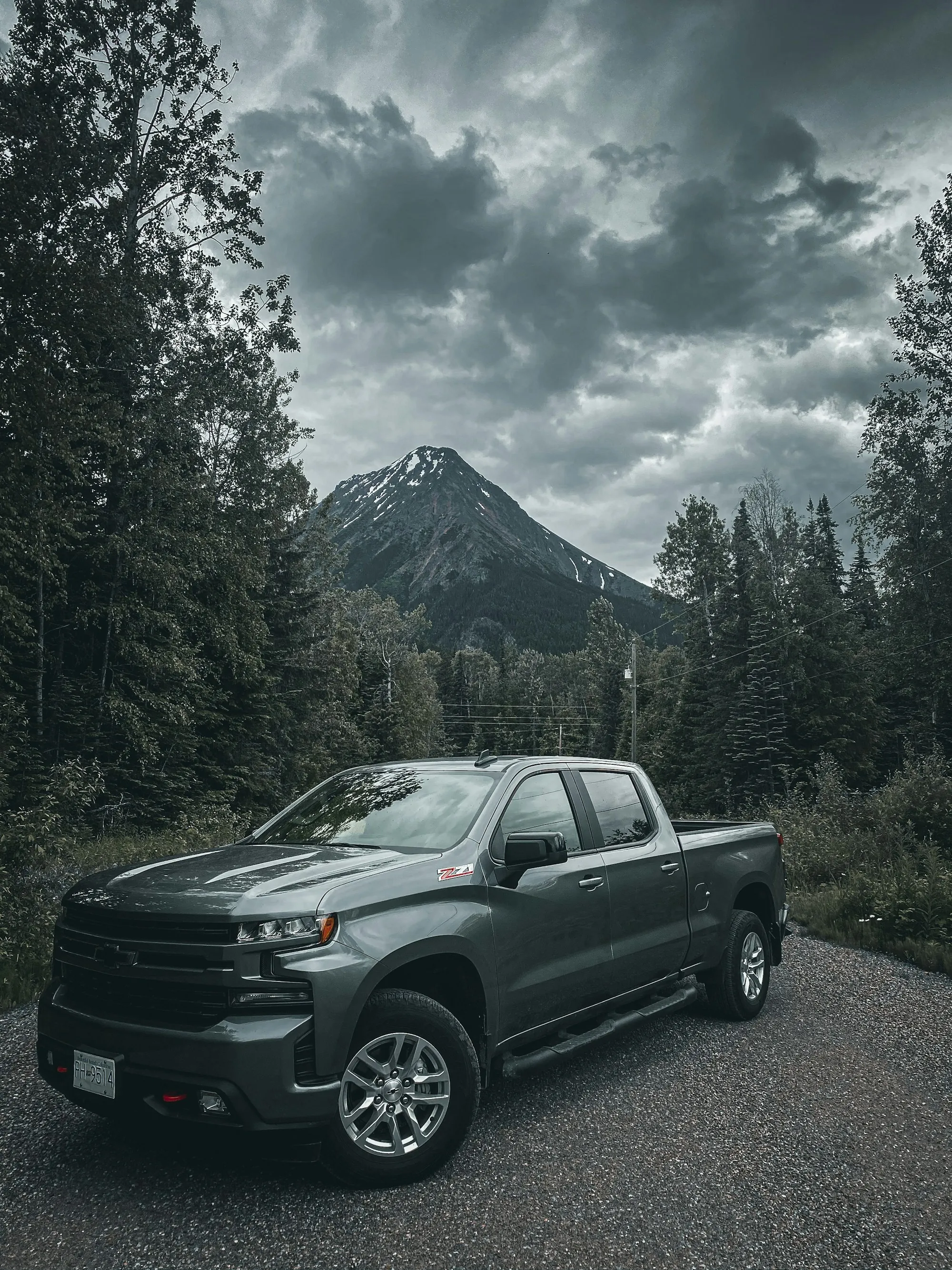 Pickup truck parked beneath a forested mountain peak