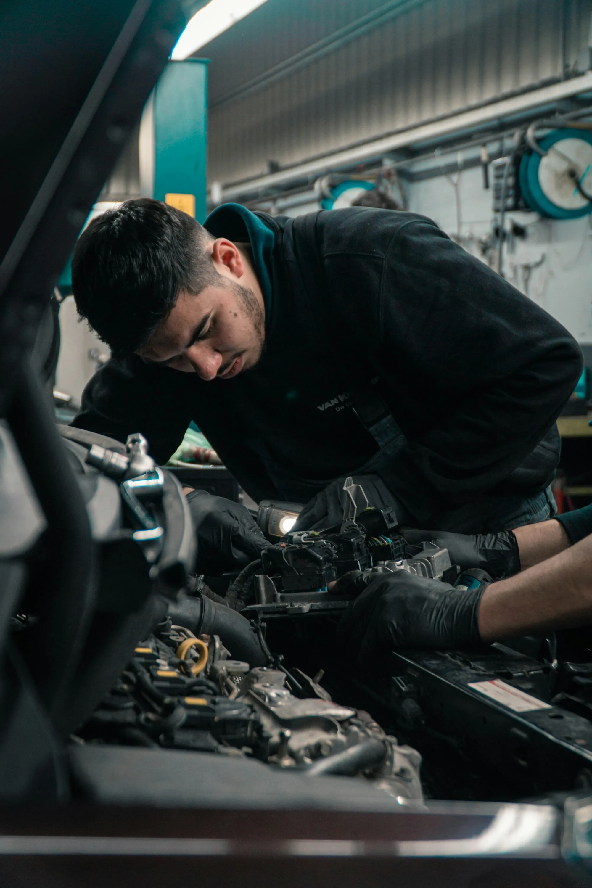 Mechanic in work clothes leaning over an engine in a repair bay