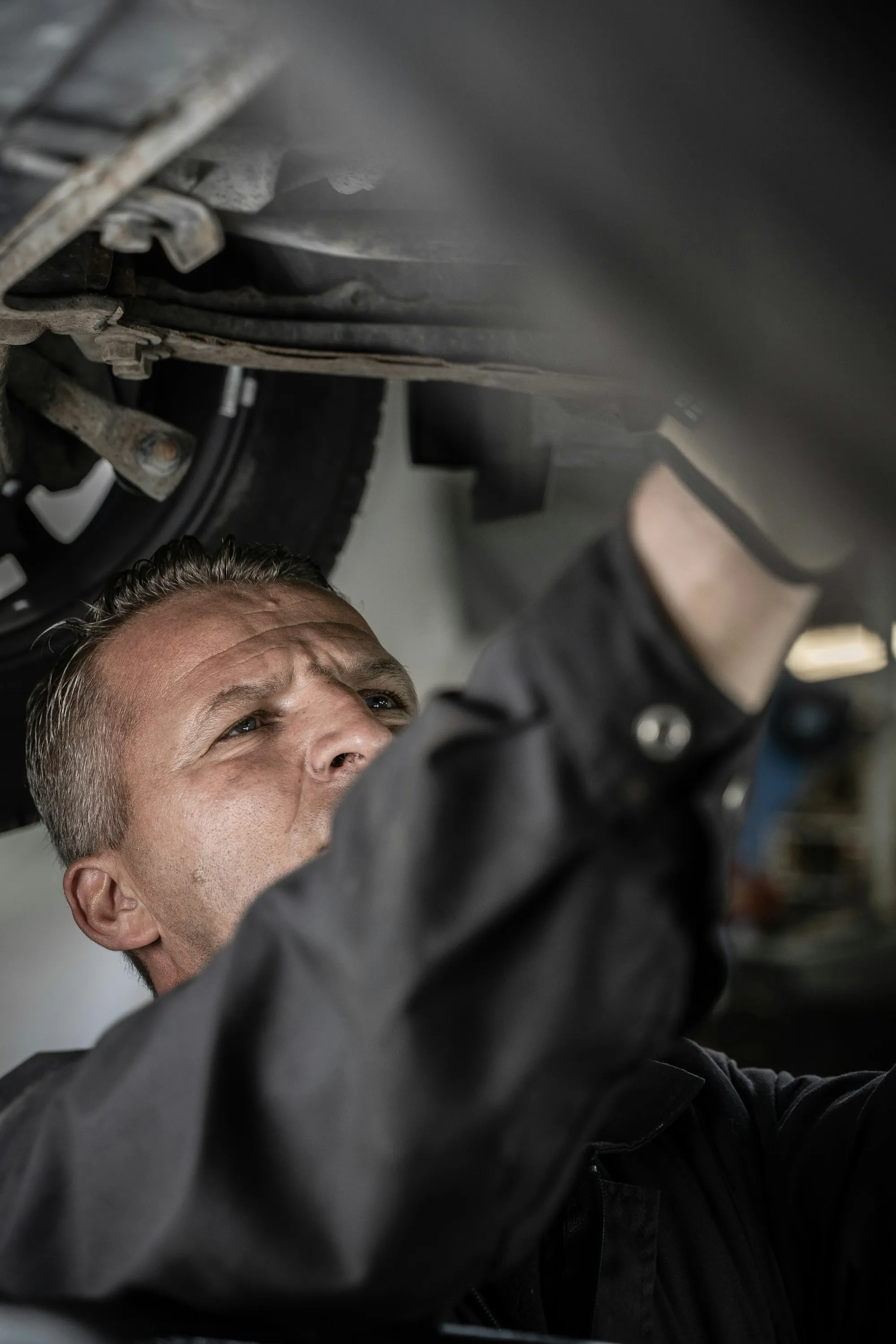 Mechanic reaching up to work beneath a raised vehicle